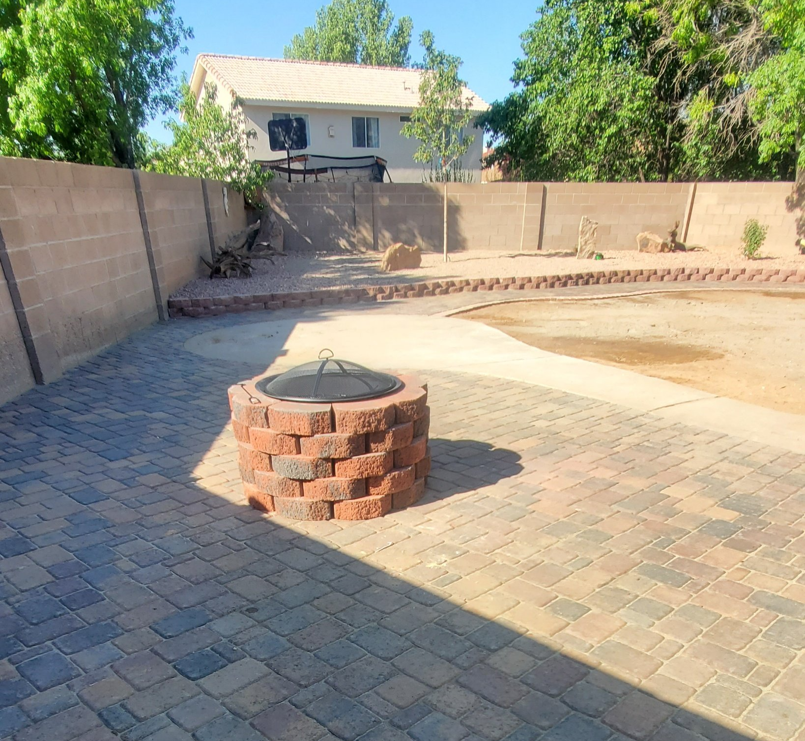 A fire pit is in the middle of a brick patio