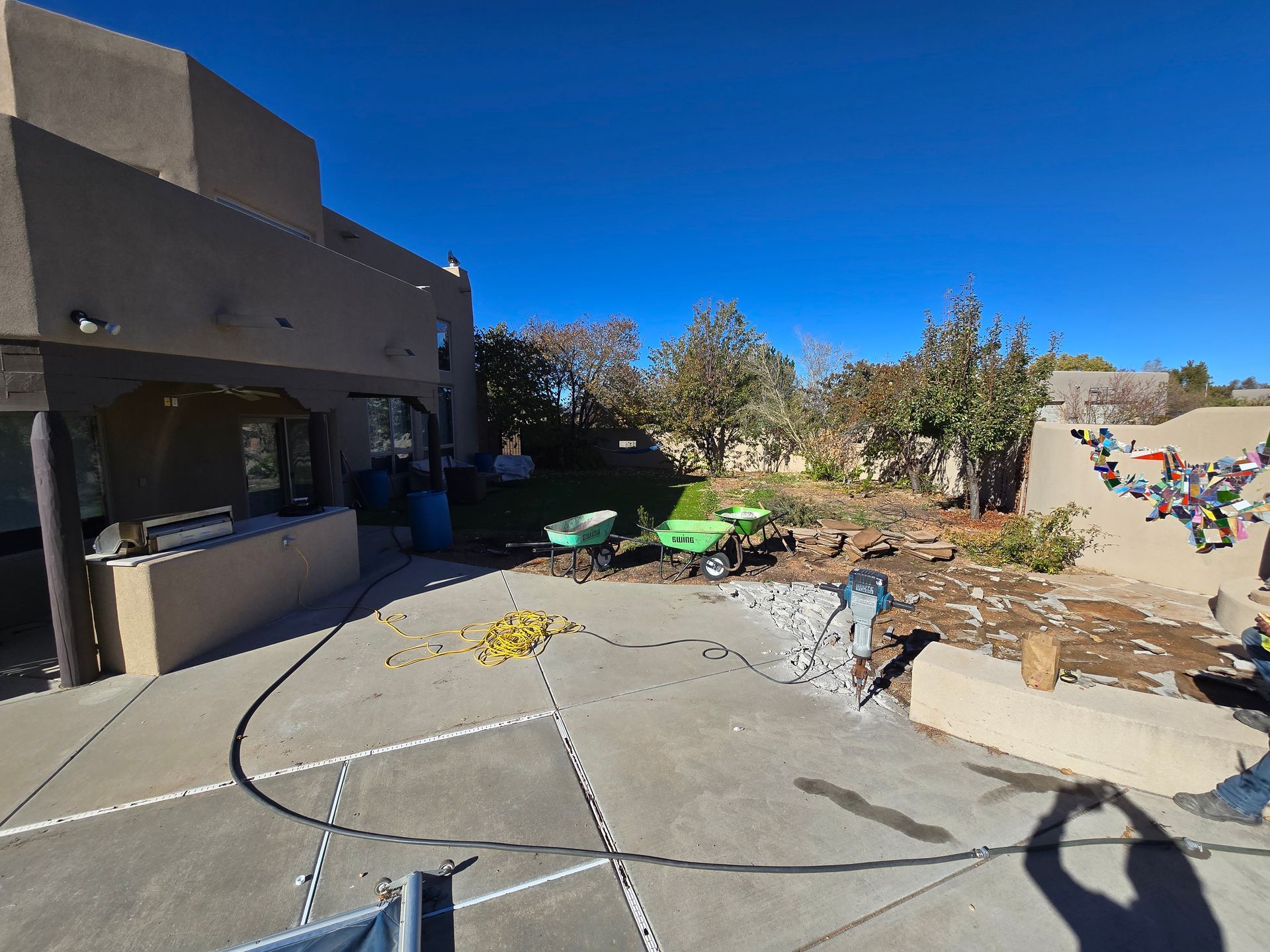 A shadow of a person is cast on a concrete driveway in front of a house.