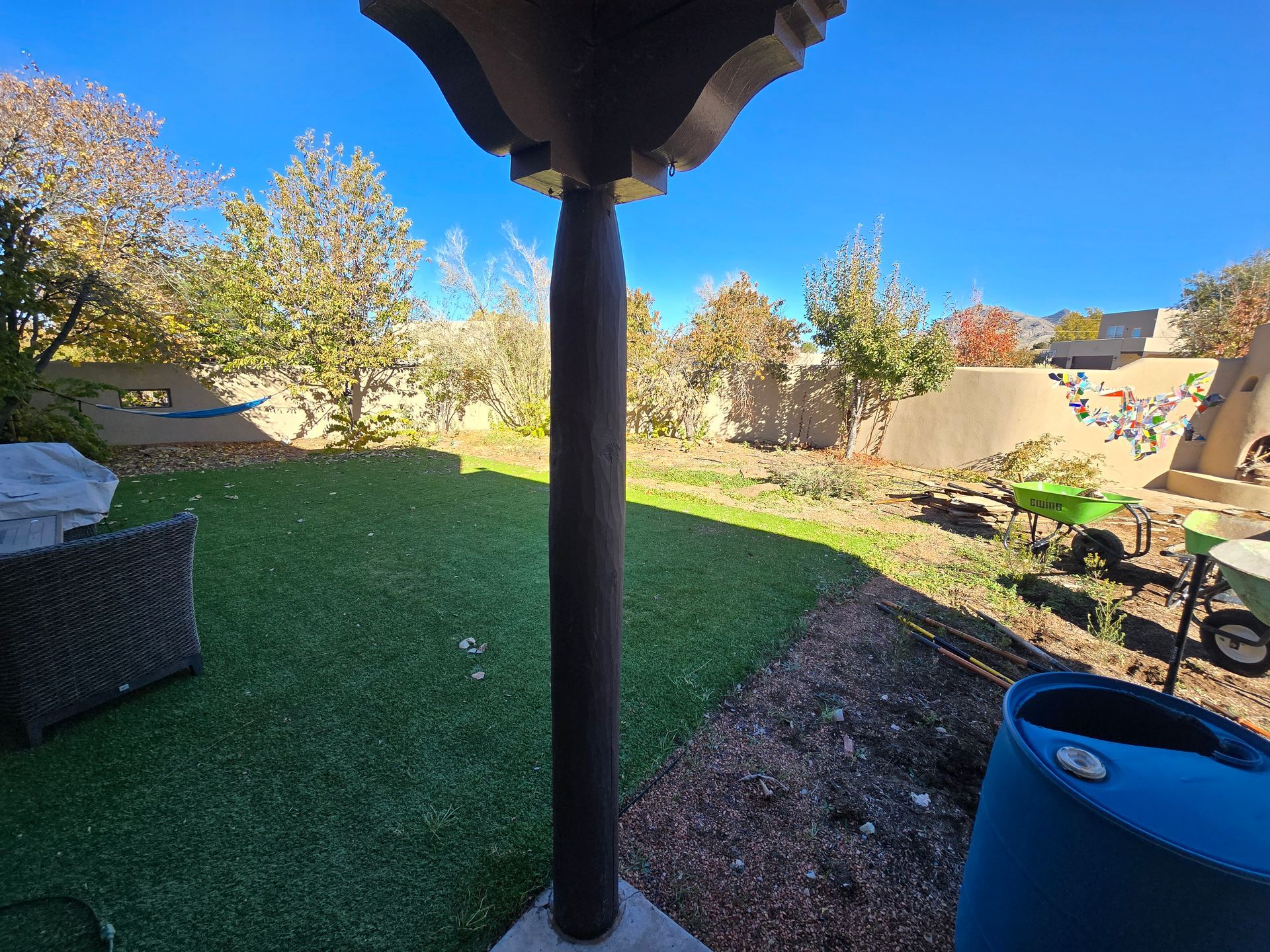 A blue barrel is sitting in the middle of a lush green yard.