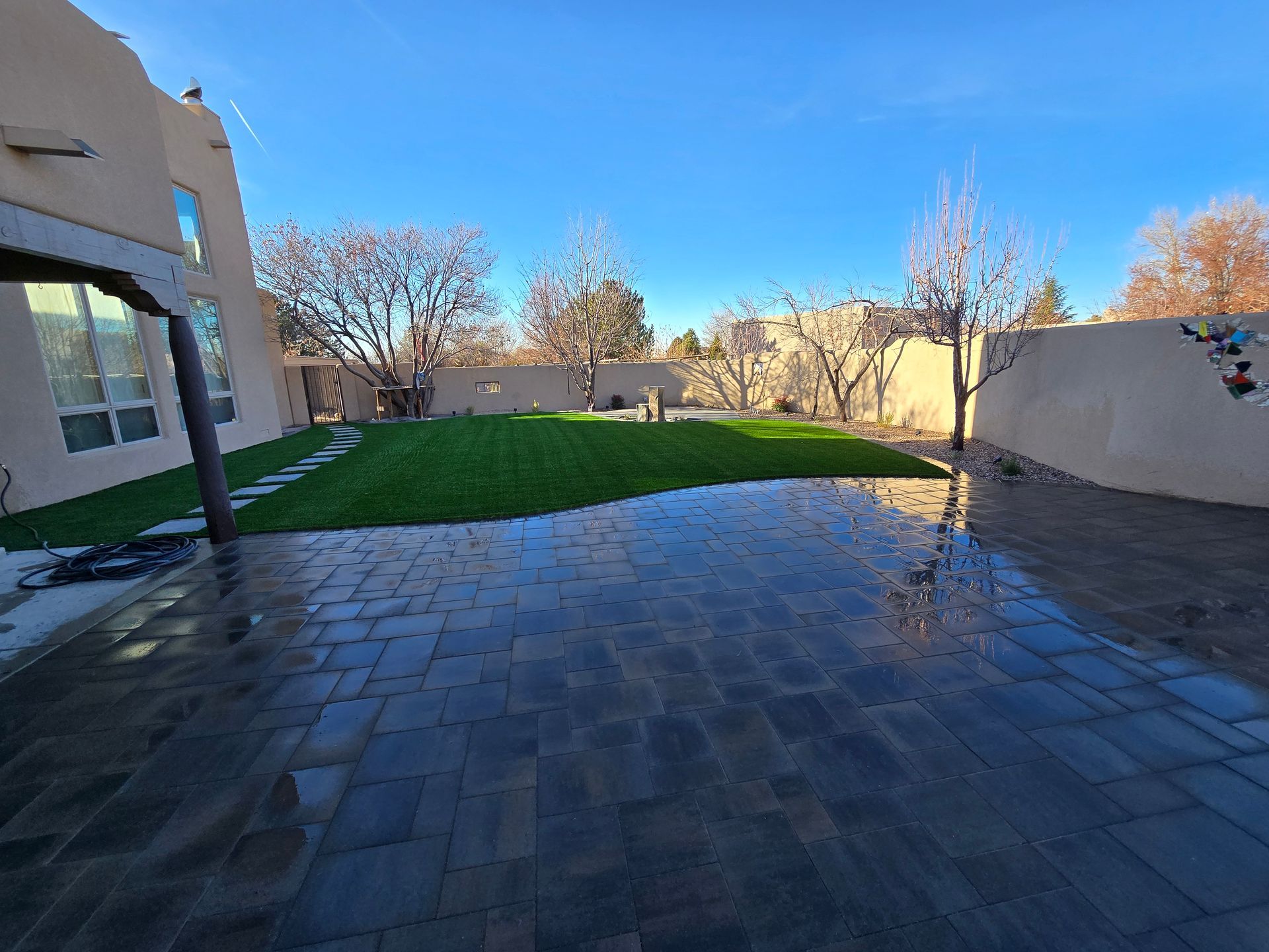 A backyard with a brick patio and a lush green lawn.