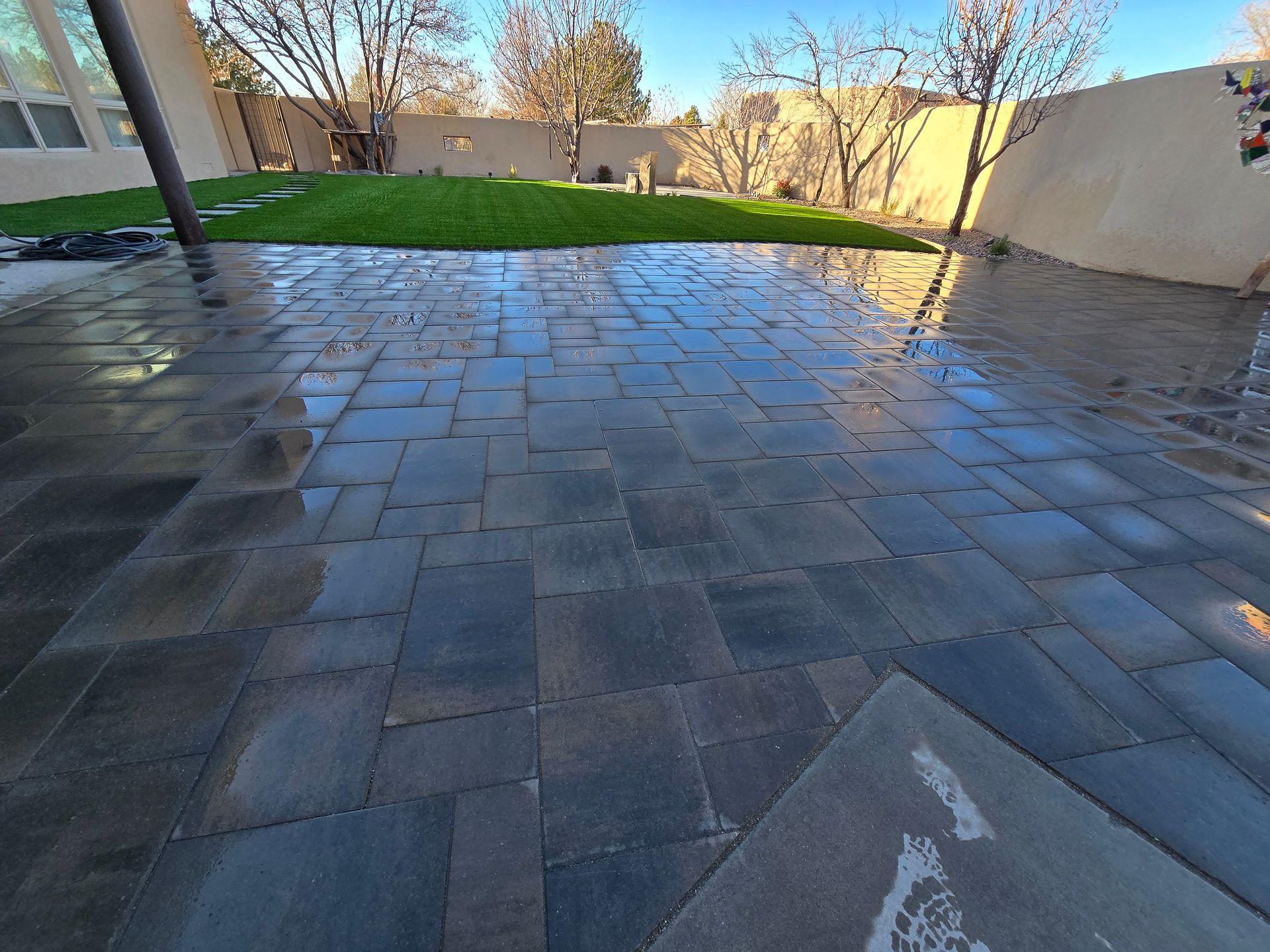 A brick patio with a lush green lawn in the background.