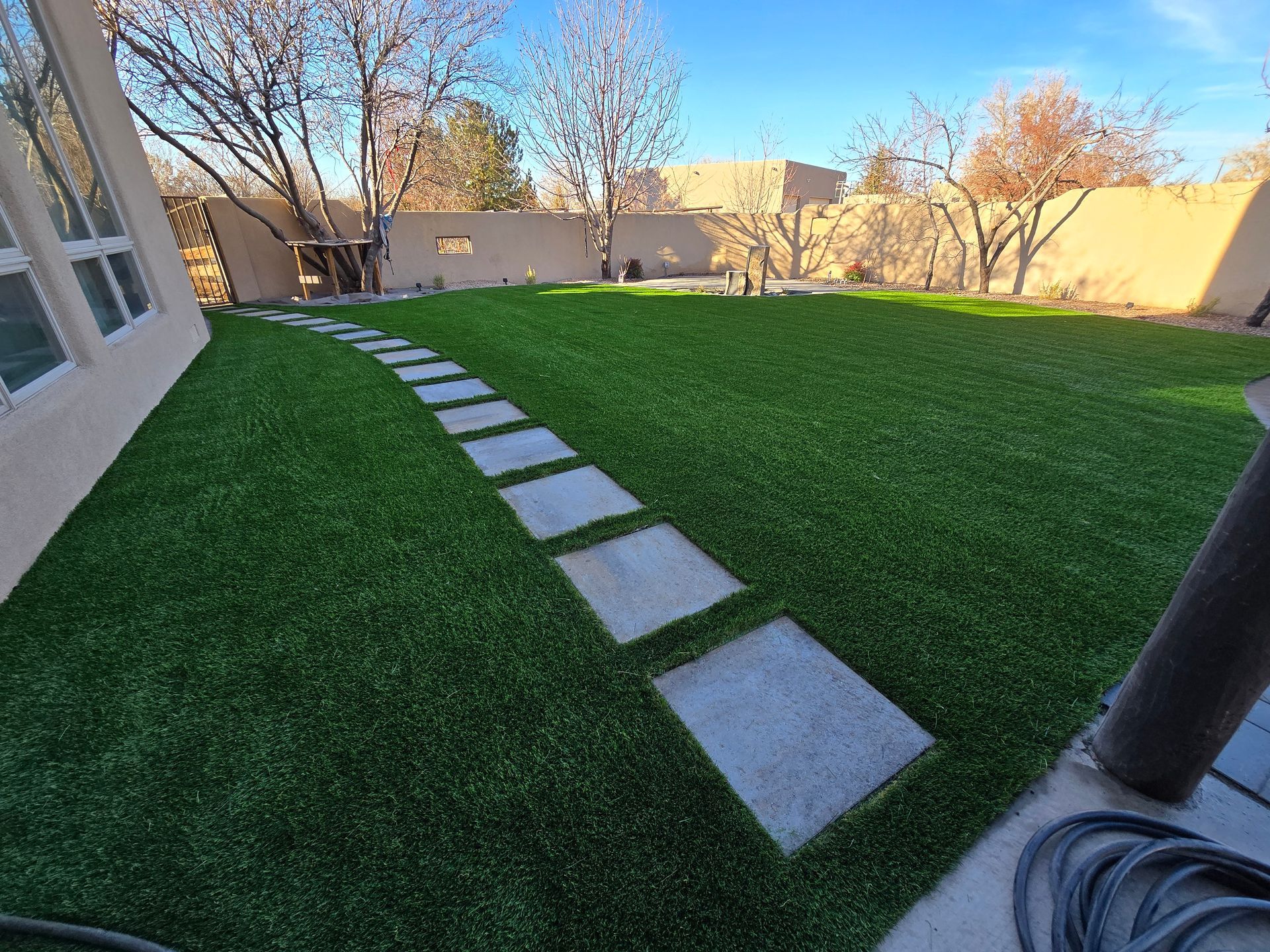 A backyard with a lush green lawn and a stone walkway.