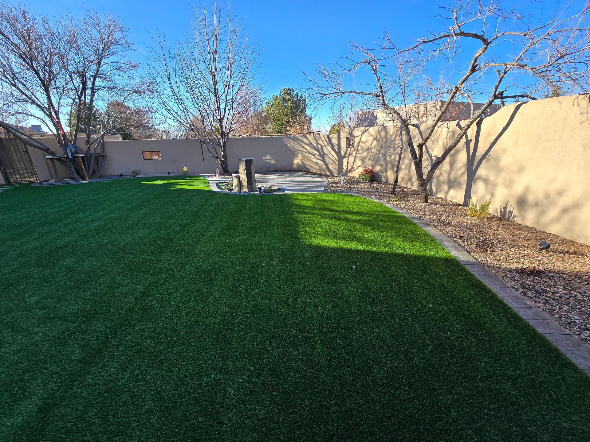A backyard with a lush green lawn and trees.
