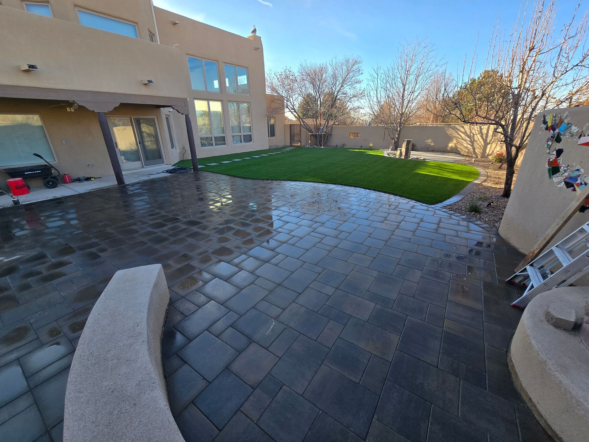 A backyard with a brick patio and a large house in the background.