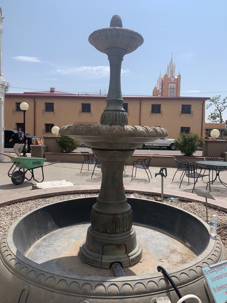 A fountain in a park with a clock tower in the background