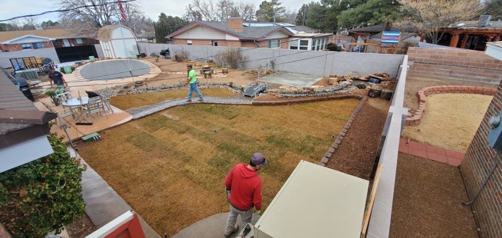A man is carrying a piece of wood in a backyard.