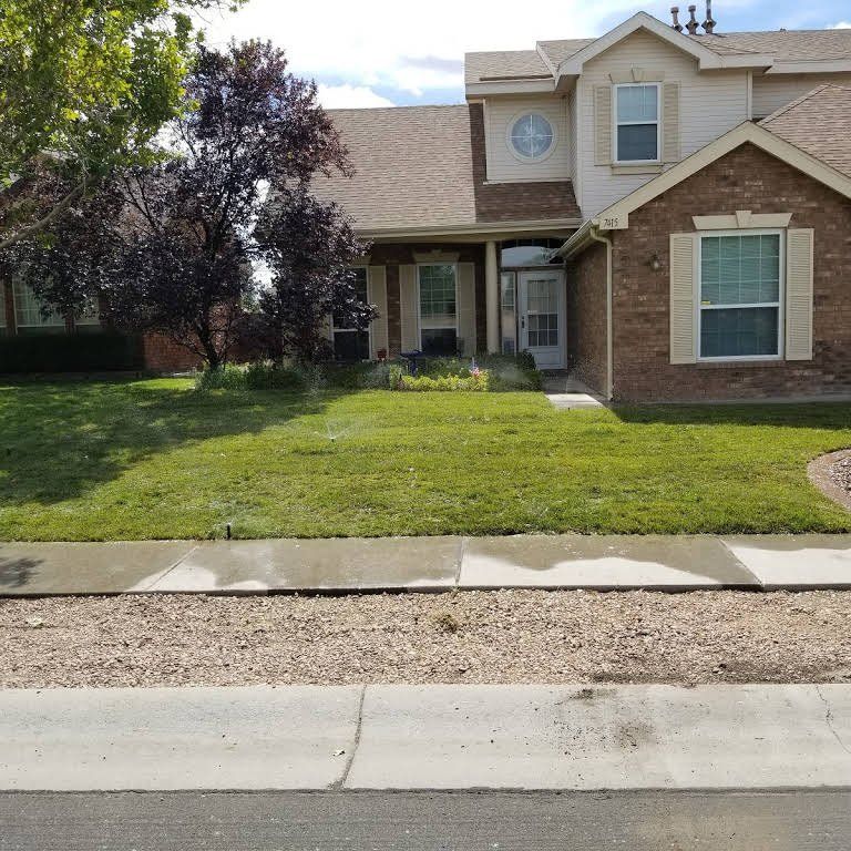 A brick house with a lush green lawn in front of it