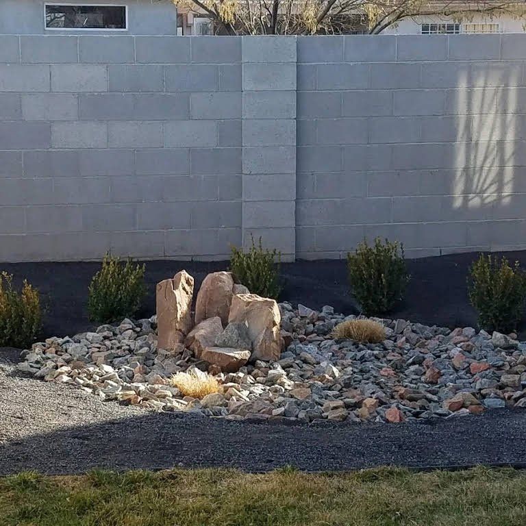 There is a rock garden in front of a brick wall.
