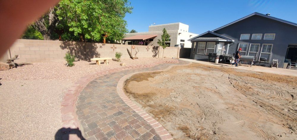 A brick walkway is being built in a backyard in front of a house.
