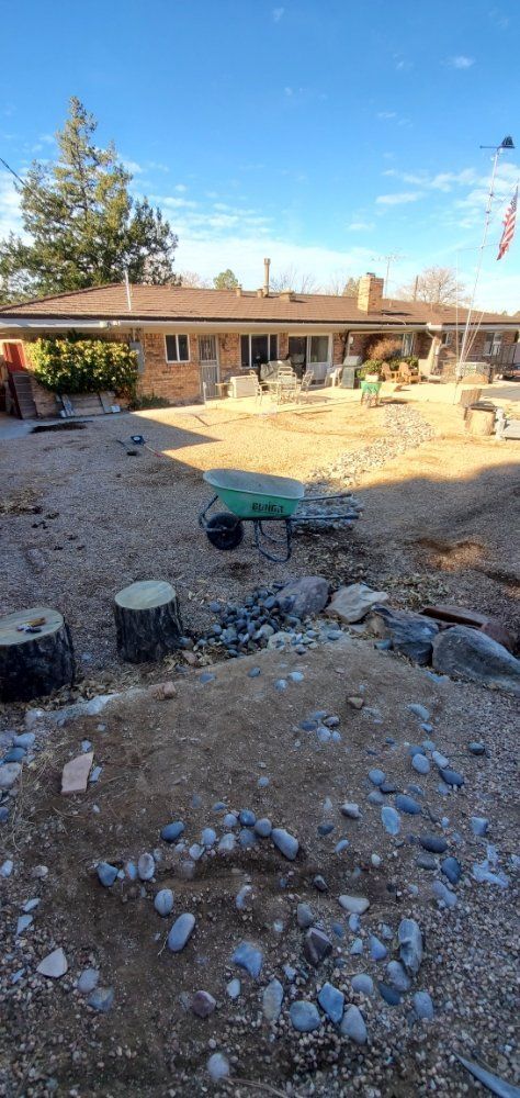 A wheelbarrow is sitting in the dirt in front of a house.