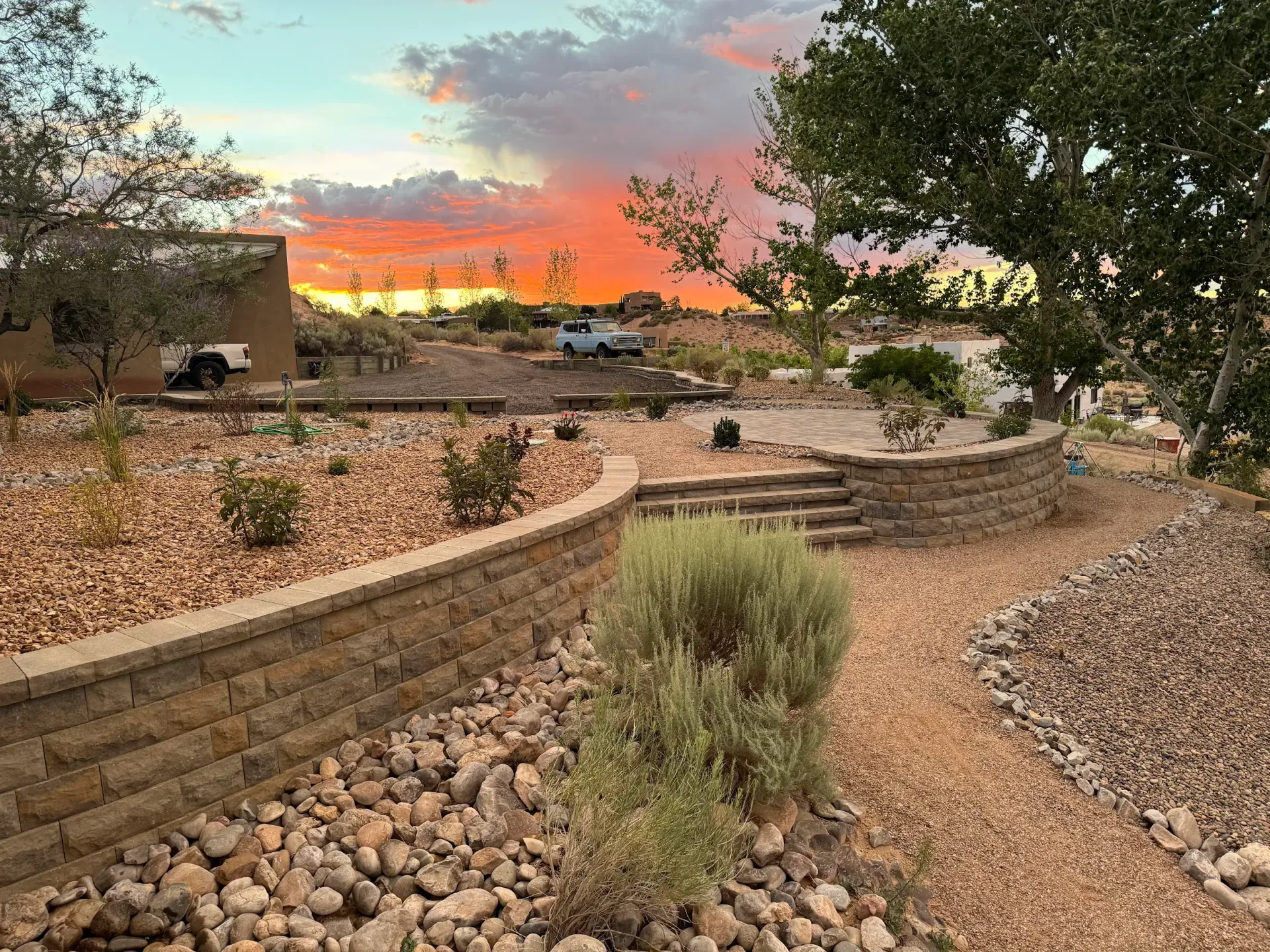There is a sunset in the background and a brick wall in the foreground.