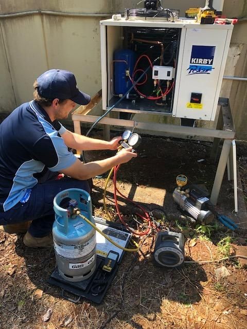 A Man Is Working on An Air Conditioner Outside of A Building — Northernair in Wollongbar, NSW