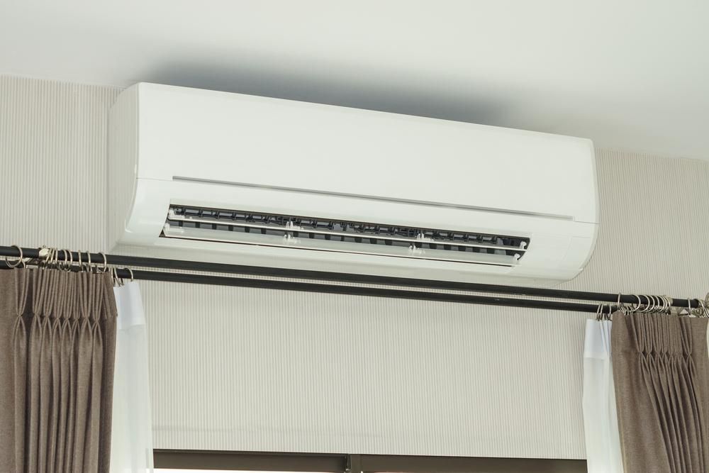 A White Air Conditioner Is Mounted to The Ceiling Above a Window — Northernair in East Lismore, NSW