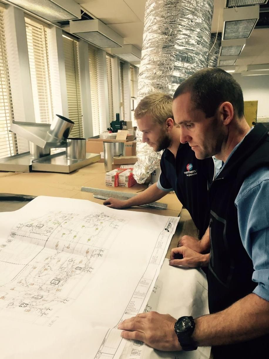 Three Men Are Looking at A Blueprint in A Room — Northernair in Nimbin, NSW
