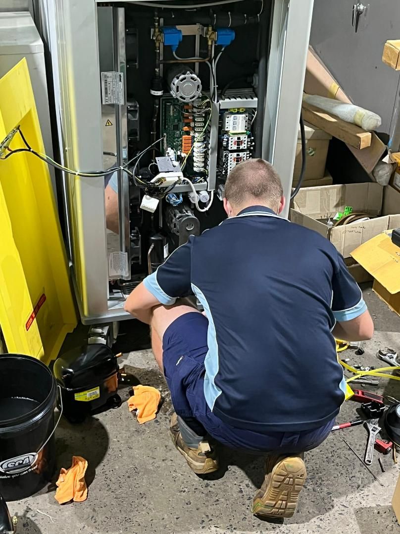 A Man Is Kneeling Down Working on A Machine — Northernair in East Lismore, NSW