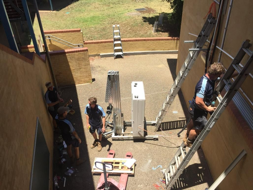 A Group of Men Are Working on A Building with A Ladder — Northernair in Alstonville, NSW