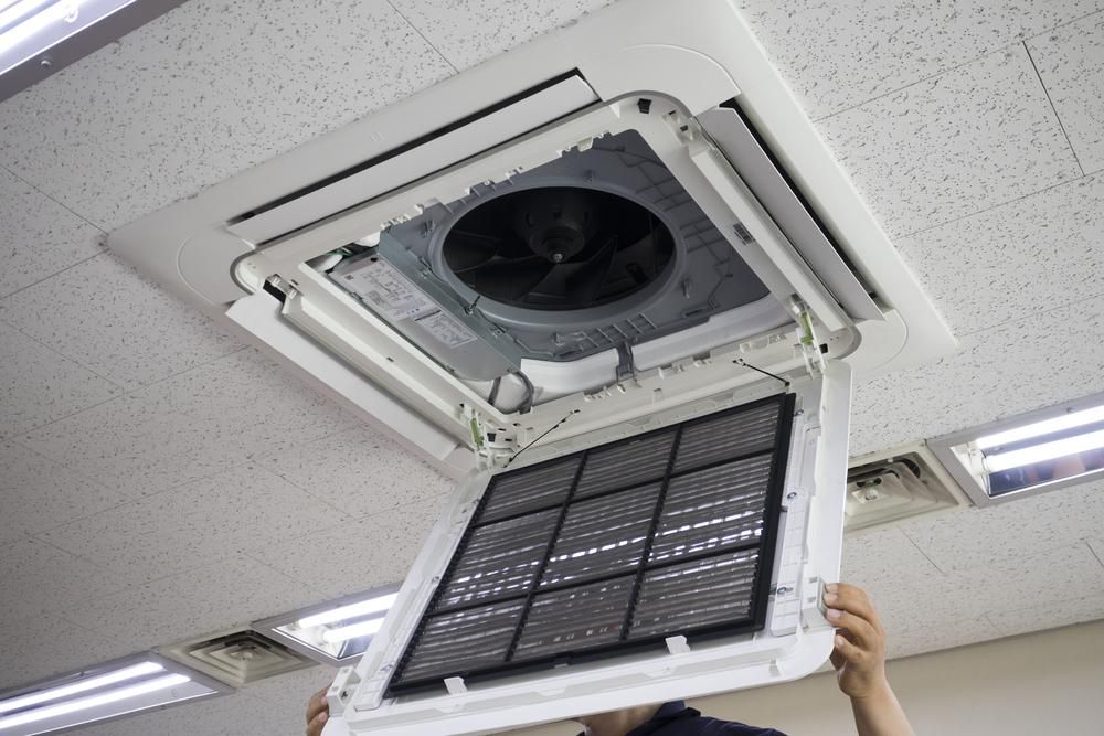 A Man Is Holding a Filter in Front of An Air Conditioner — Northernair in Nimbin, NSW