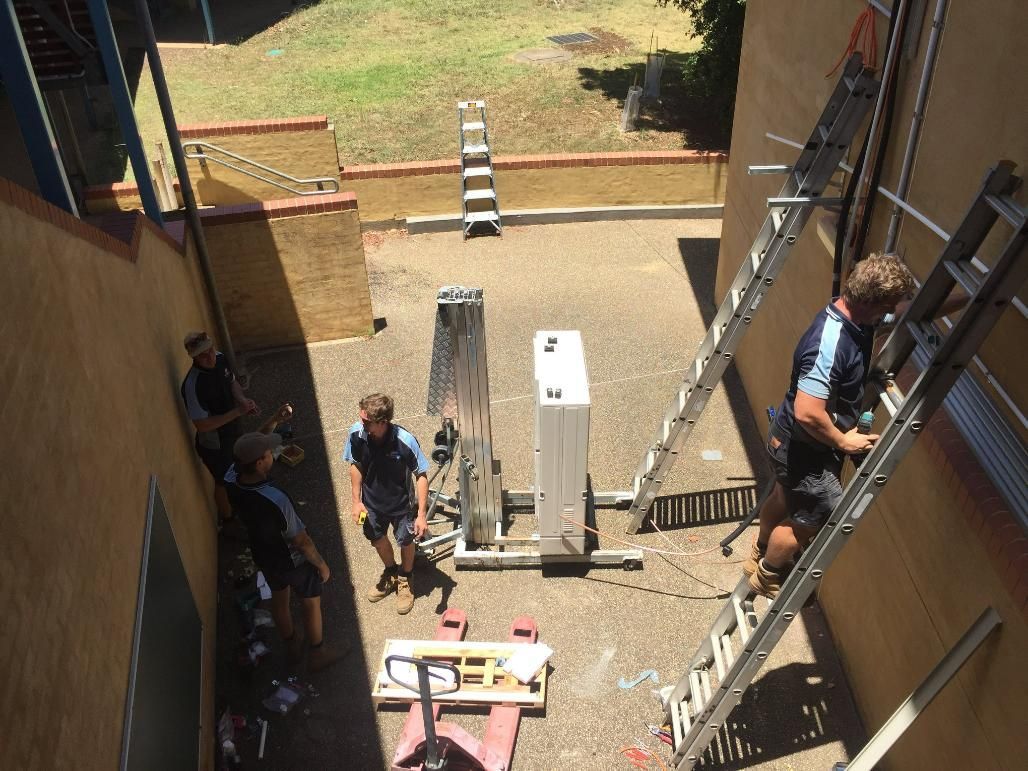 A Group of Men Are Working on A Building with A Ladder — Northernair in East Lismore, NSW