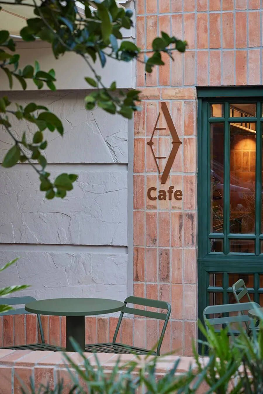 Entrada al café del hotel con mesas al aire libre y decoración de ladrillo