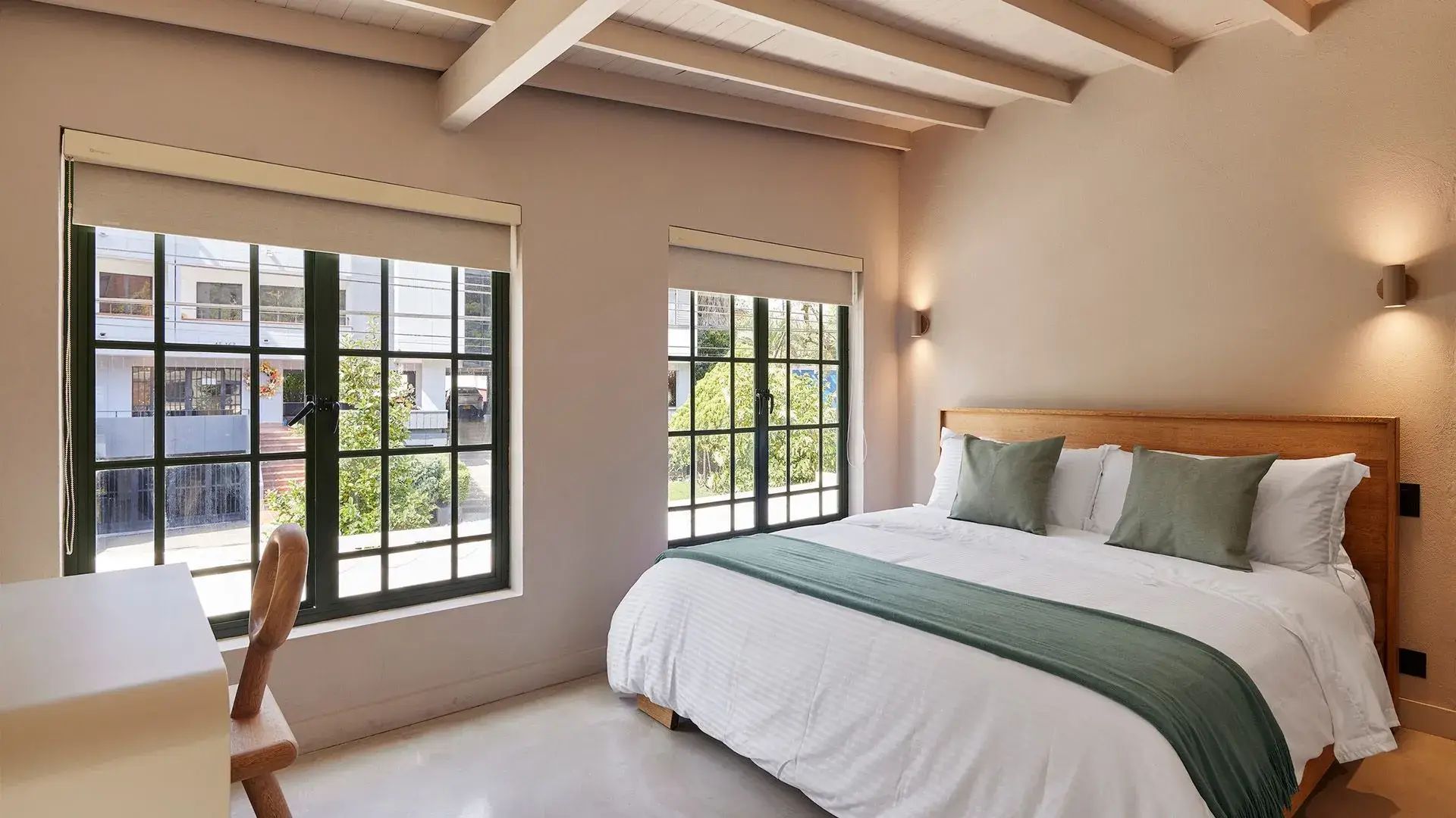 Dormitorio de la suite superior Lombok en el Antípoda Hotel Boutique Medellín, con cama grande, grandes ventanales y decoración moderna y acogedora