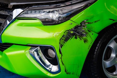 A green car with a damaged bumper is sitting on a blue surface | F & M Automotive Body & Repair