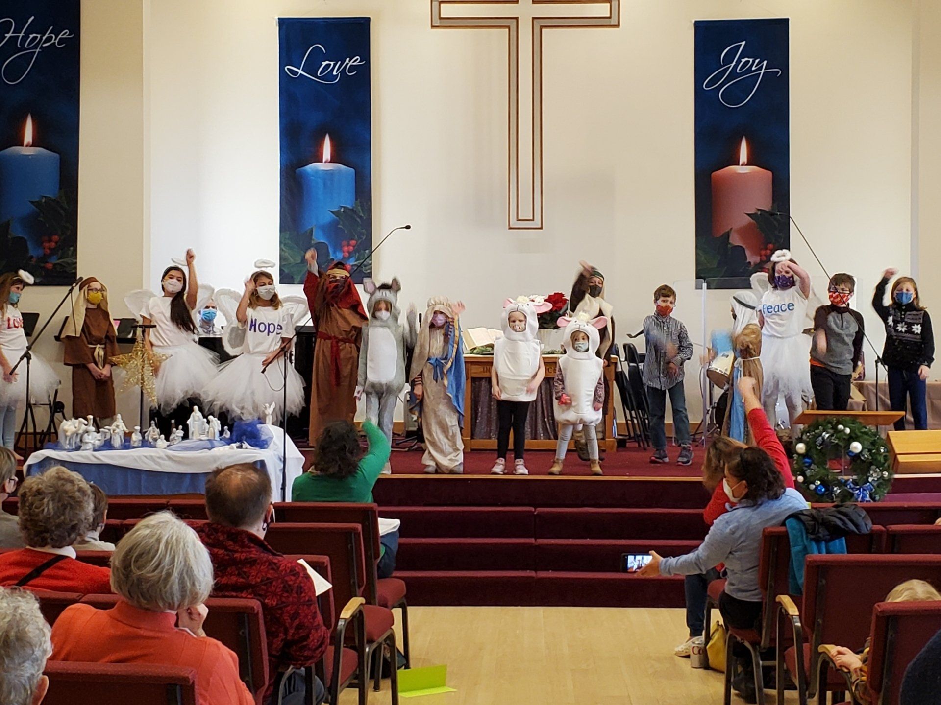 Children performing a Christmas pageant on a church stage; audience watches from pews.