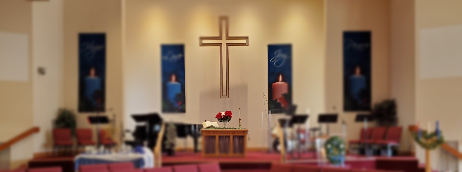 Church interior with cross, banners, altar, and musical instruments on a stage.