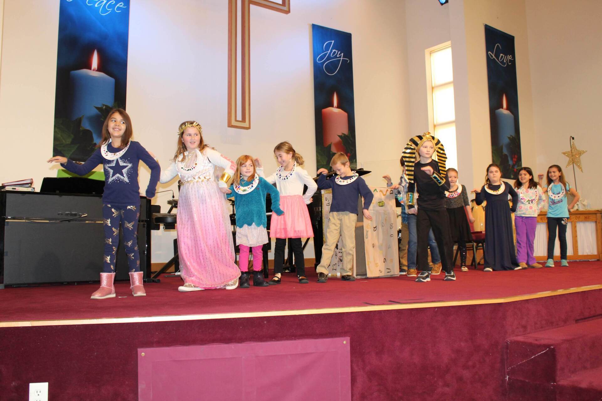 Children in costumes performing on a stage in a church.