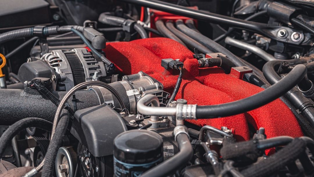 Close-up of a car engine with black hoses, silver components, and a red air filter.