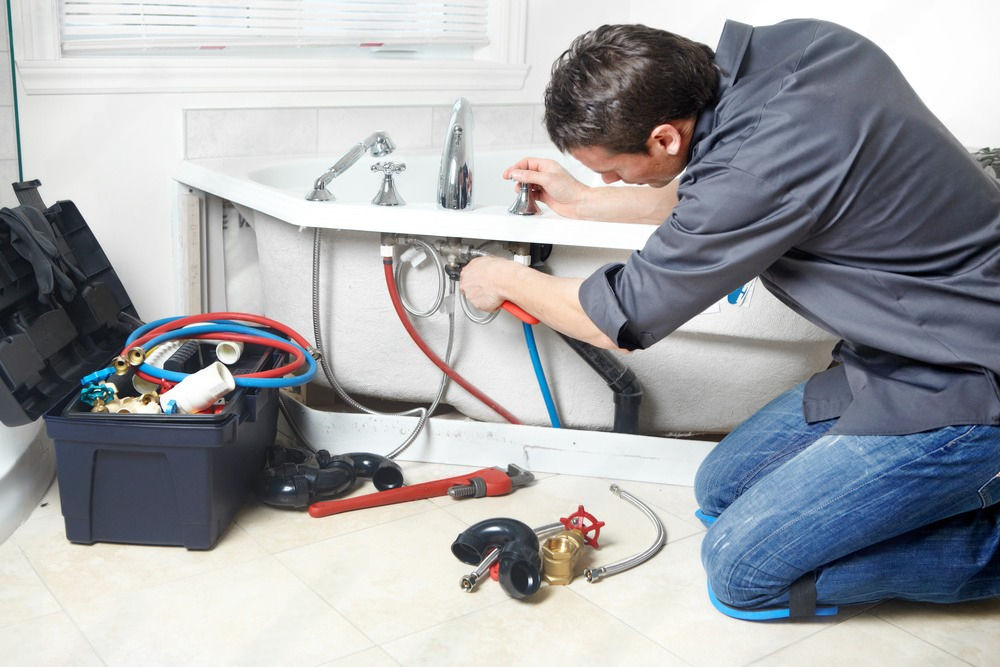 a plumber is working on a bathtub in a bathroom .