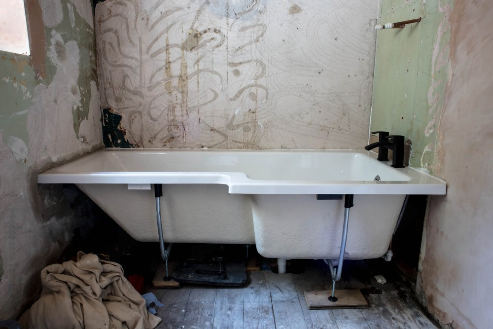 a bathtub is sitting in a bathroom with a dirty wall .