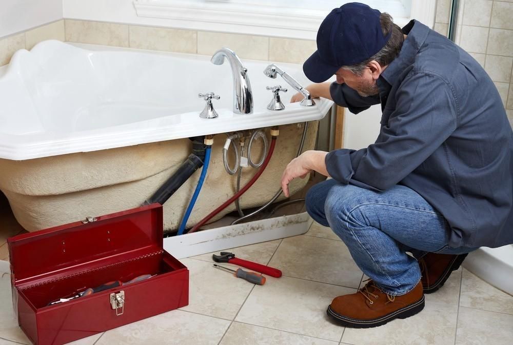 a plumber is working on a bathtub in a bathroom .