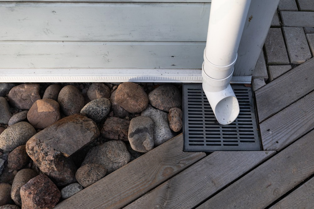 a white pipe is connected to a drain on a wooden deck .