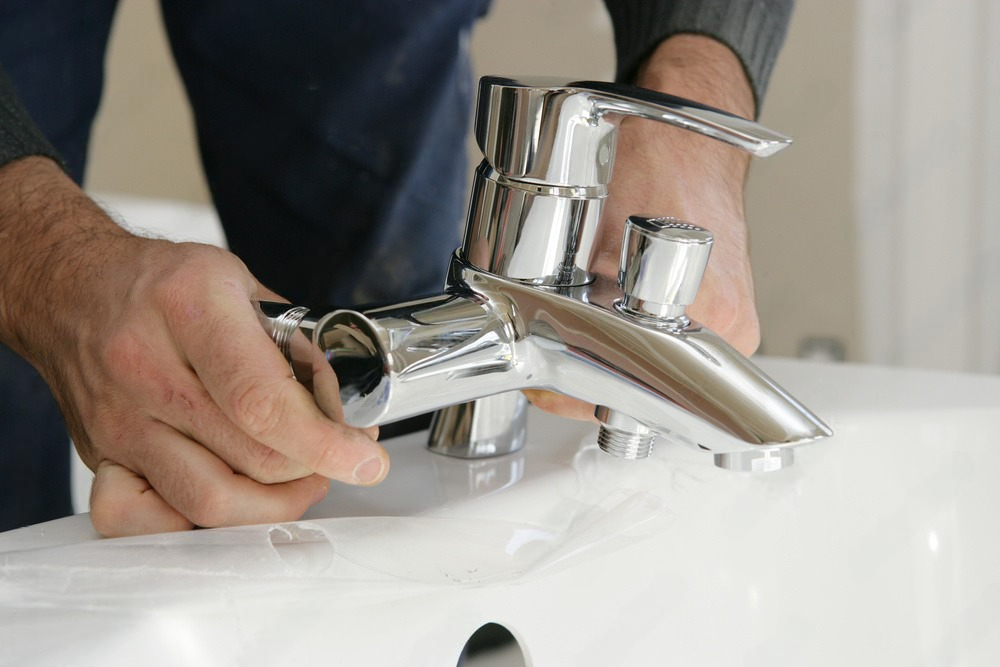 a man is fixing a faucet on a sink .