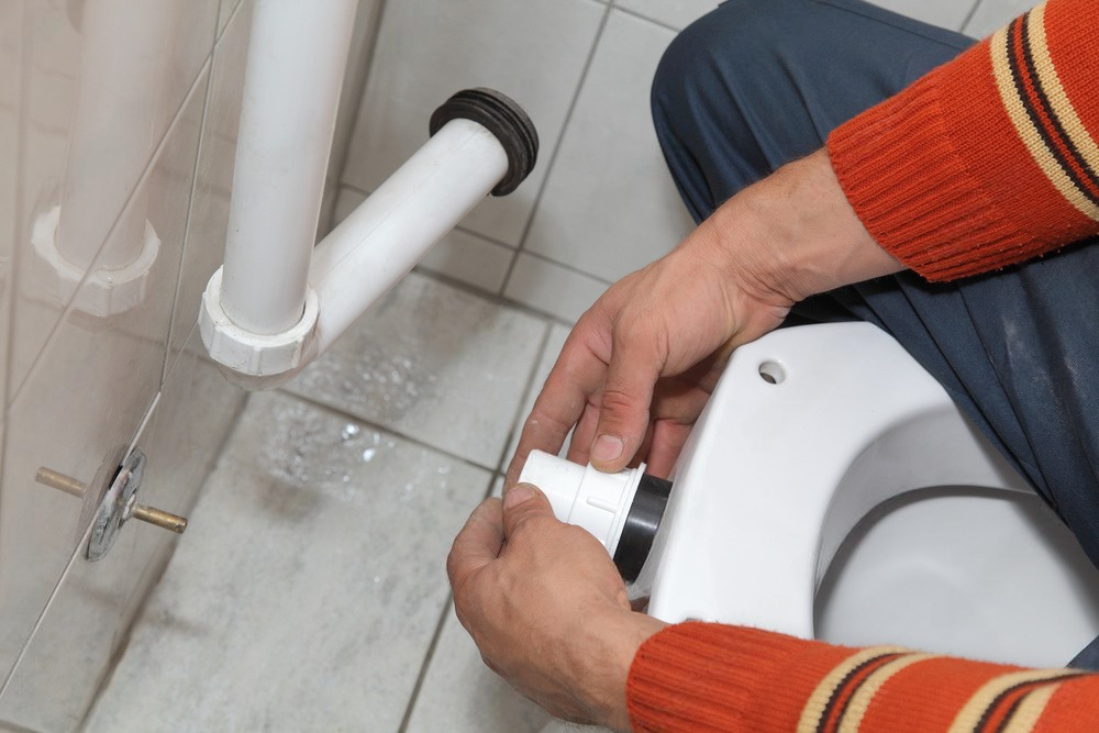 a man is fixing a toilet in a bathroom .
