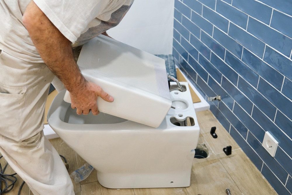 a man is installing a toilet in a bathroom .