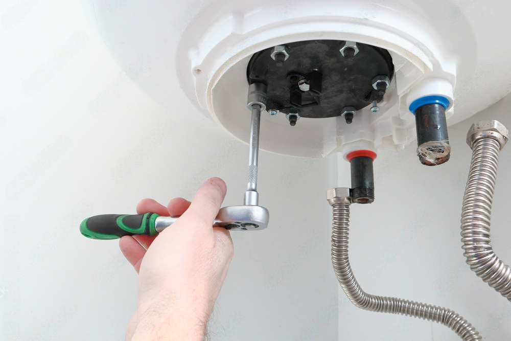 a person is fixing a water heater with a wrench .