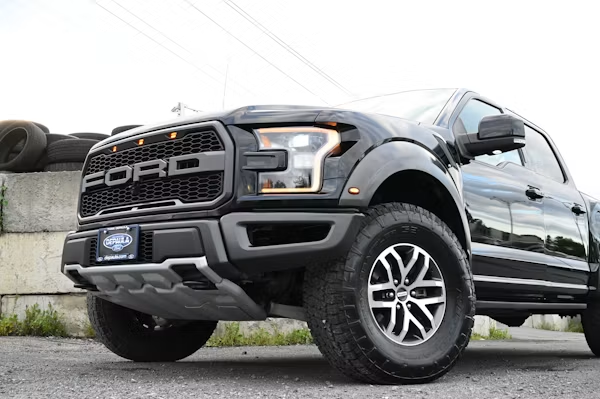 Black Ford pickup truck parked outdoors, low-angle front view with off-road tires.