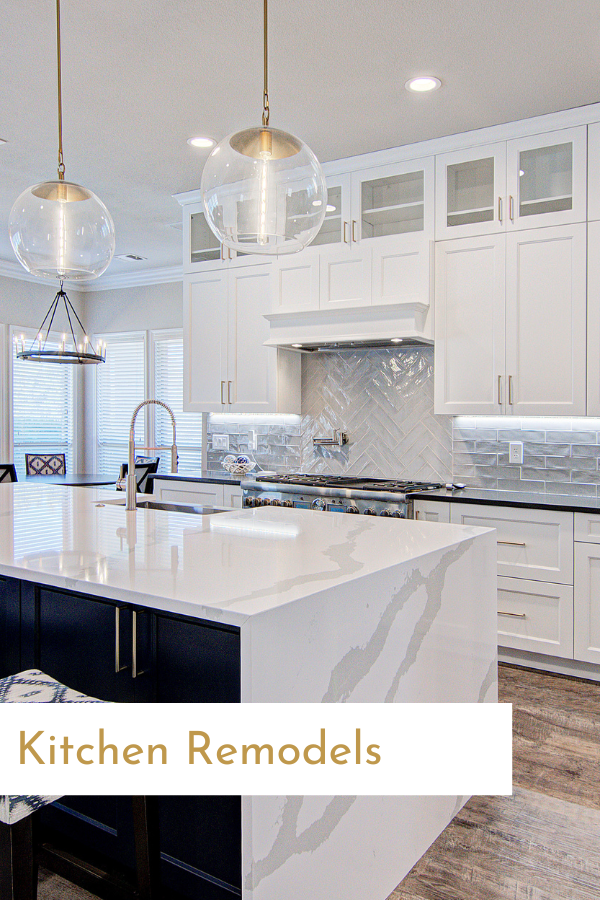 A kitchen with white cabinets , black counter tops , and a large island.