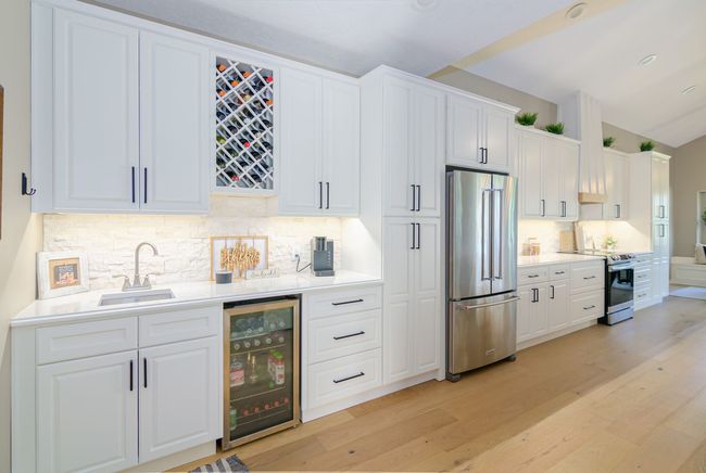 A kitchen with white cabinets , stainless steel appliances and a wine cooler.