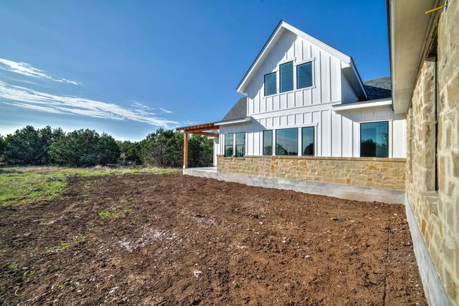 A white house with a lot of windows is sitting on top of a dirt field.