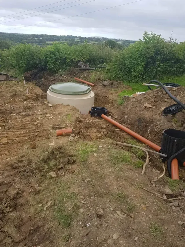 Construction site with buried septic tank and drainage pipes in an outdoor setting.