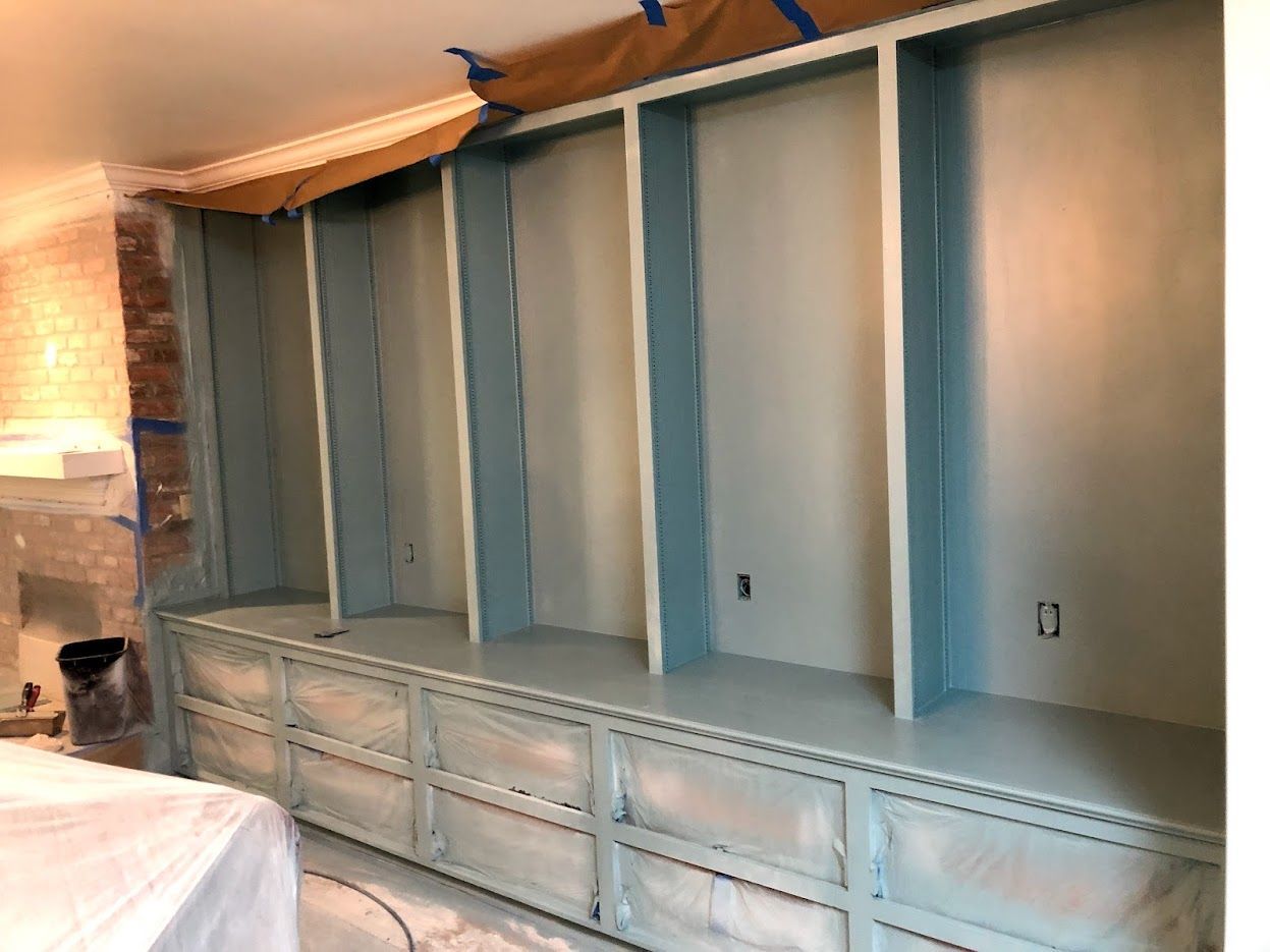 Built-in shelving unit being painted light blue and white; a work in progress in a room.