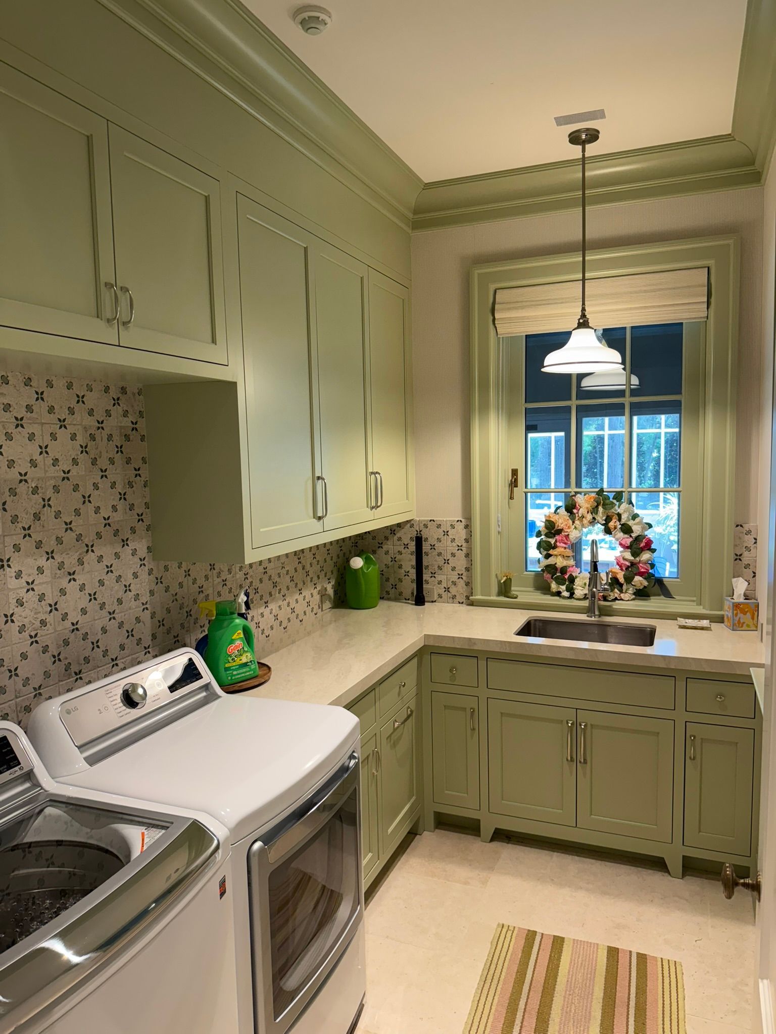 Mint-green kitchen with white appliances, marble counters, and a window over the sink.
