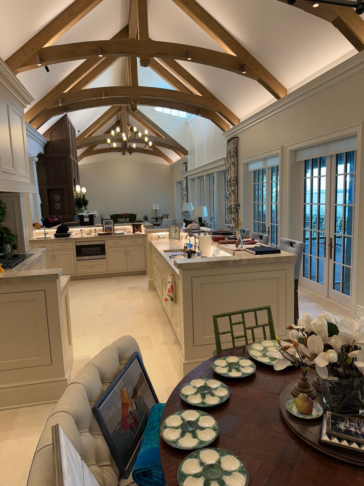 Elegant dining room with exposed beams, white tables, and set place settings by tall windows.