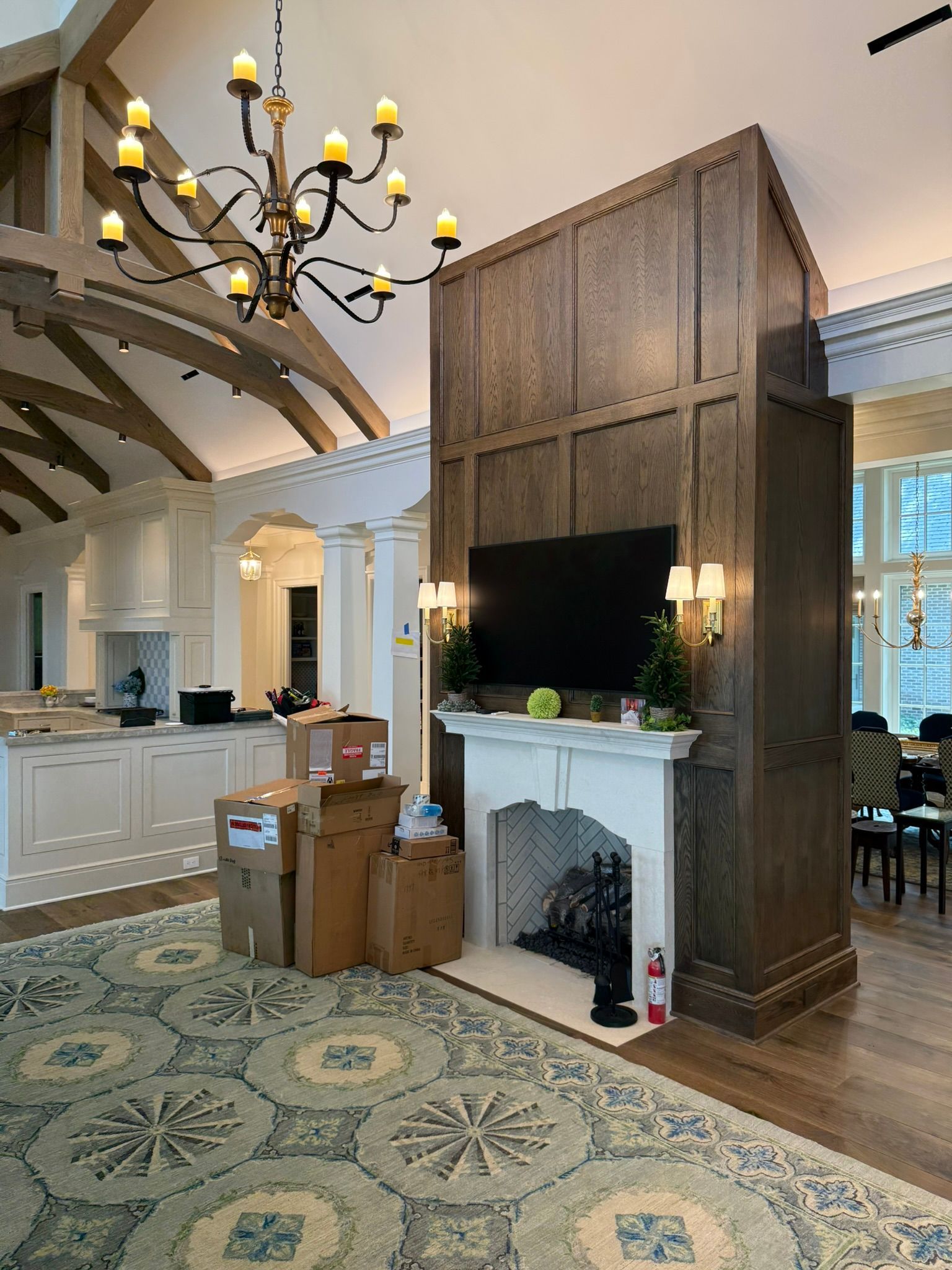 Elegant living room with wood-paneled fireplace, large TV, chandelier, and patterned rug