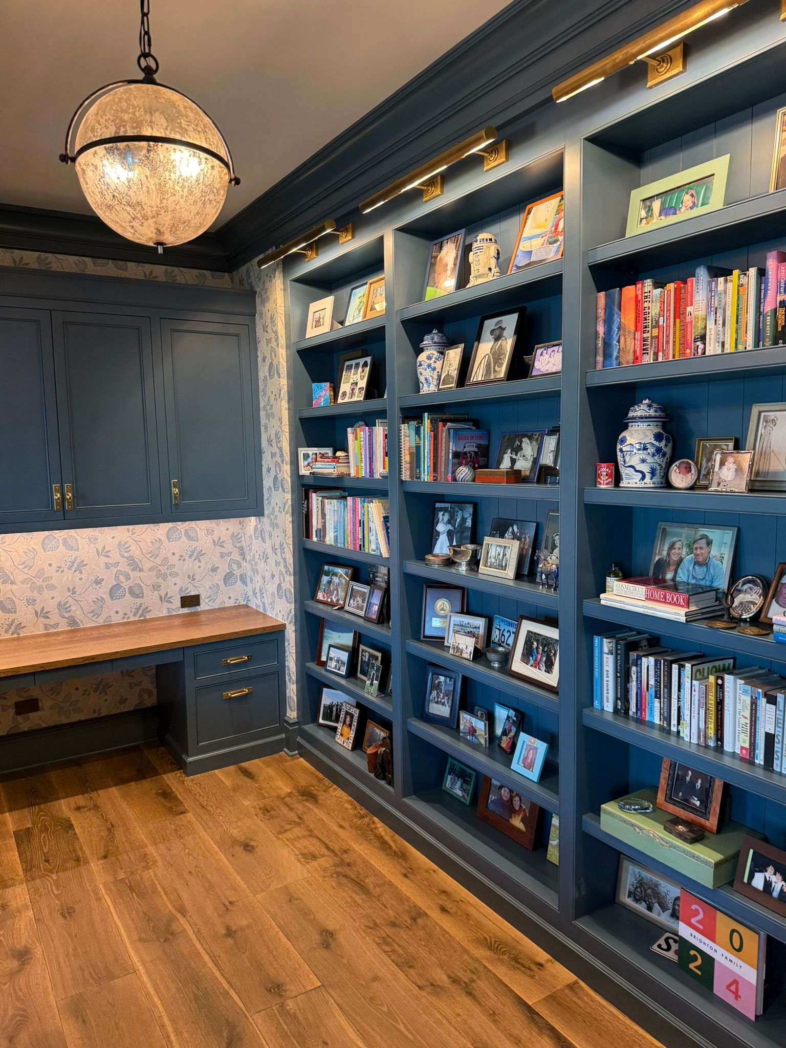 Blue bookshelves filled with books and photos in a home office with wood flooring and a desk.