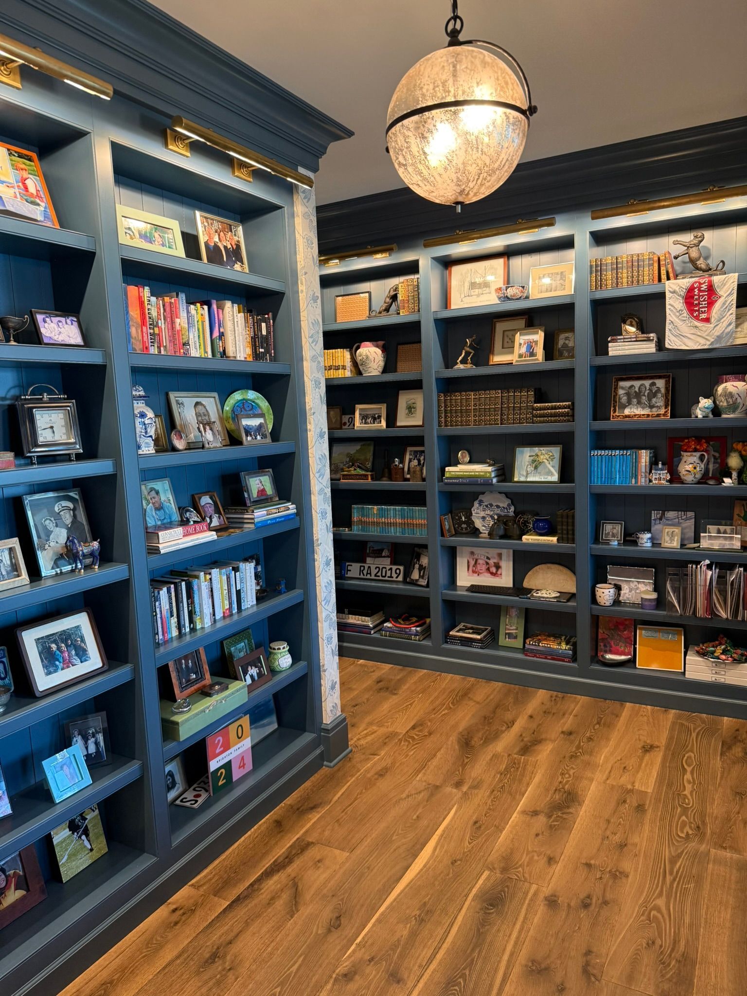 Bookstore interior with dark blue shelves, colorful books, and a hanging globe light over wood floors