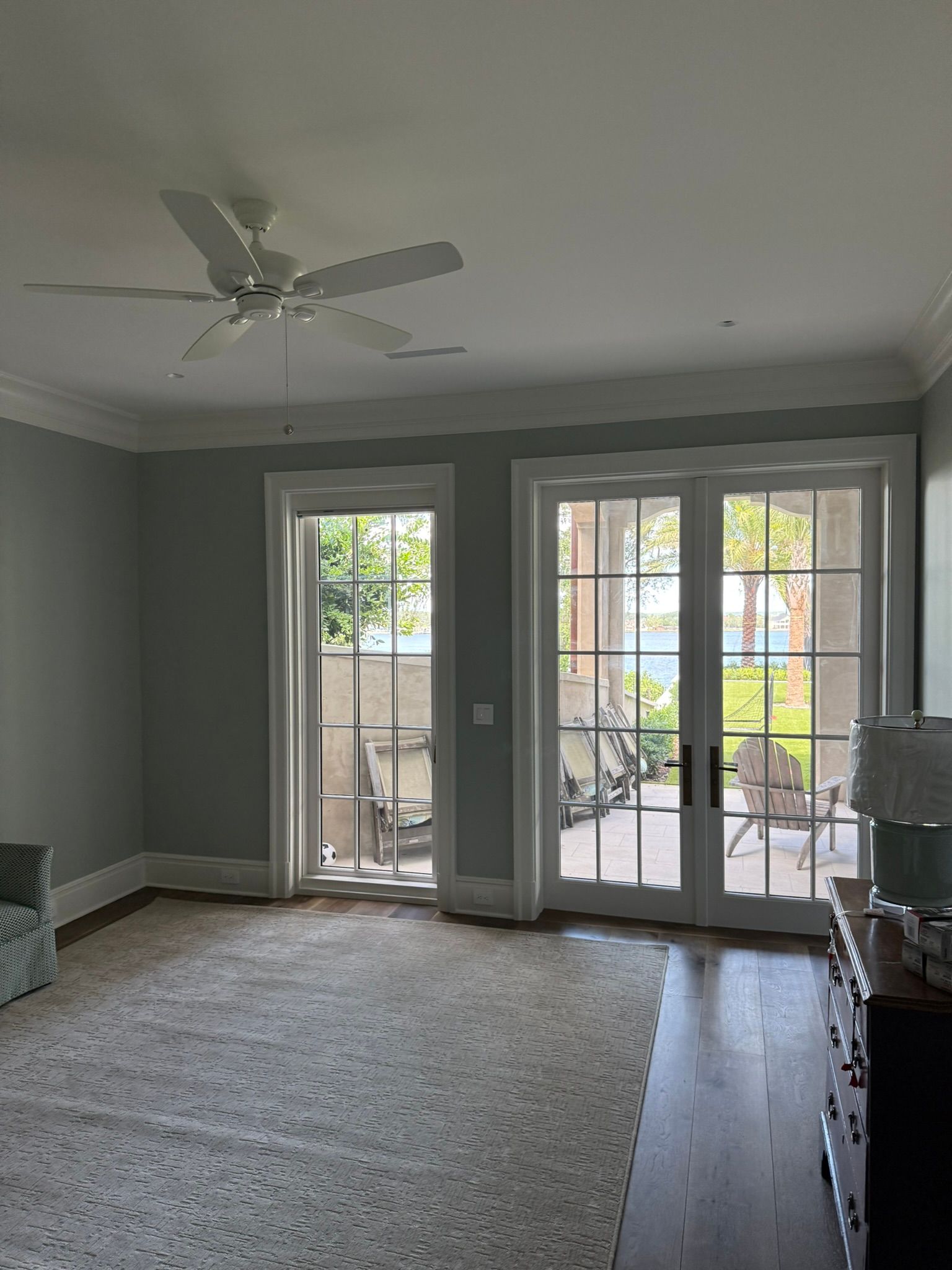 Empty living room with gray walls, carpet, ceiling fan, and French doors to a patio.