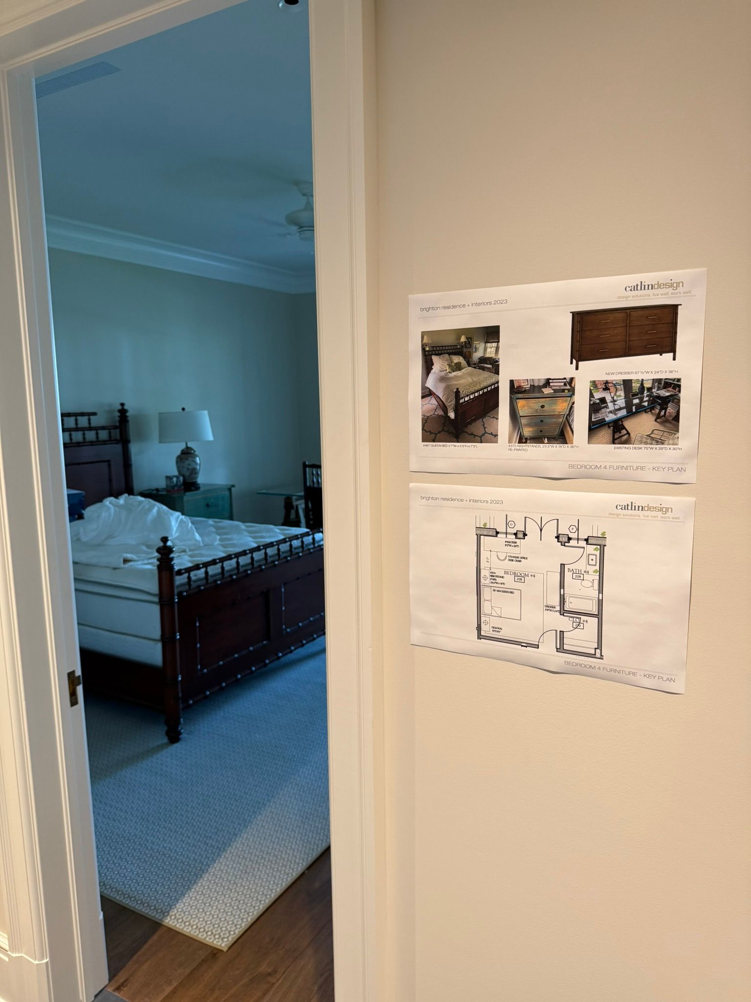 Hallway view into a bedroom with a dark wood bed; photos and a floor plan are taped to the wall.